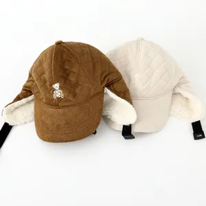 Close-up of quilted winter earflap hats with bear embroidery and lamb wool lining