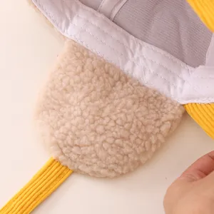 Detailed view of yellow corduroy fabric and warm beige faux shearling lining on earflap hat