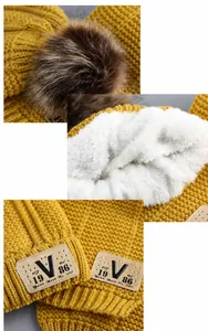 Detail view of ginger yellow knit hat with rabbit fur pom-pom and thick fleece lining