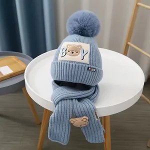Detailed close-up of light blue knit hat with faux fur pom and cartoon bear embroidery