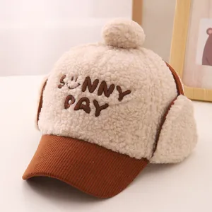 Detail of plush beige earflap hat with brown corduroy brim and Sunny Day embroidery
