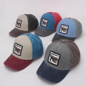 Detail of colorful washed cotton baseball caps with embroidered dinosaur patches