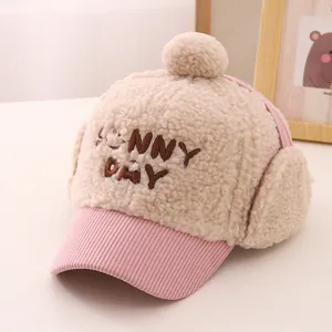 Detail of winter plush earflap hat for kids featuring SUNNY DAY embroidery and pompom
