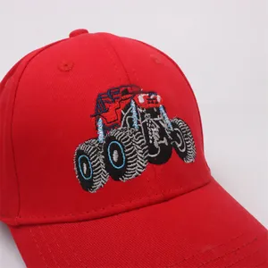 Close-up of red kids baseball cap with detailed monster truck embroidery and cotton texture