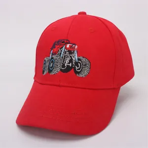 Detail of red kids baseball cap featuring colorful monster truck embroidery and cotton fabric