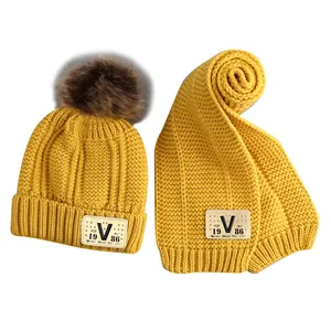 Winter ginger yellow knitted baby hat and scarf set with V-label and pompom detail
