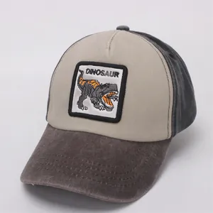 Close-up of dinosaur embroidery patch on beige and dark grey kids baseball cap