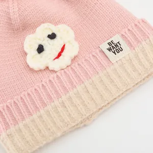 Detail der rosa Strickmütze mit Wolken-Aufnäher und BE WANT YOU Stoffetikett