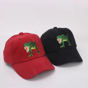 Detail of embroidered green dinosaur on red and black cotton kids baseball caps