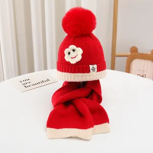 Detail des rot-weißen Strickmützen-Sets für Kinder mit Bommel und Blumen-Applikation