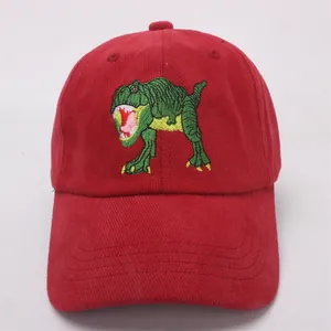 Close-up of red corduroy baseball cap featuring a green dinosaur embroidery detail