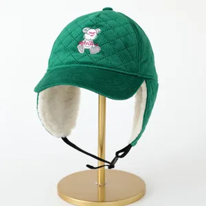 Detalle del gorro de aviador verde acolchado con bordado de oso y forro polar blanco