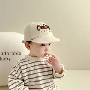 Detail van beige baby honkbalpet met Create borduursel en zachte katoenen textuur