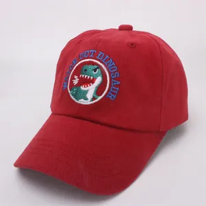 Detail of red corduroy kids baseball cap with dinosaur embroidery and text patch