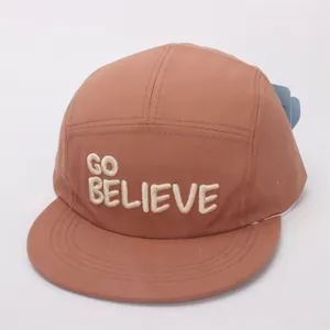 Close-up of GO BELIEVE embroidery on the front of the brown cotton five-panel camper hat