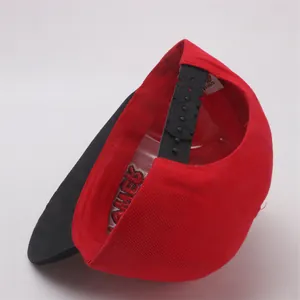 Detail shot of the red and black snapback hat with adjustable plastic strap and inner tag