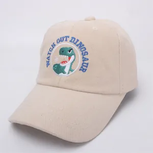 Detailed macro view of the dinosaur embroidery on this beige cotton baseball cap for kids