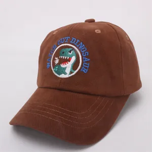 Close-up of brown corduroy kids cap featuring a green cartoon dinosaur embroidery patch