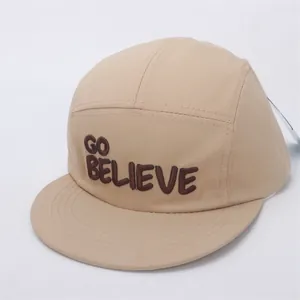 Detail of khaki five-panel cap featuring GO BELIEVE embroidery and canvas texture