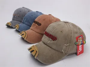 Detail of washed cotton baseball caps with 3D embroidery and distressed brim effect