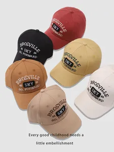 Flat lay showing multiple colors of embroidered SKY baseball caps for kids in soft cotton