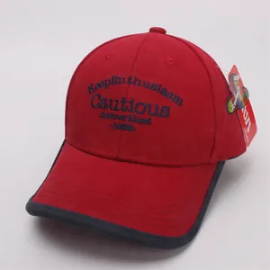 Detail of red cotton baseball cap with blue embroidery and black contrast brim piping