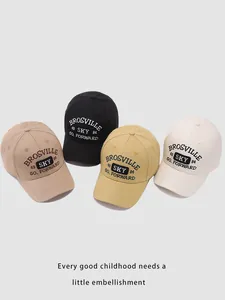 Detail showing embroidered letters on four casual cotton baseball caps in different colors