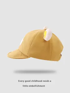 Detail einer gelben Baby-Baseballkappe aus Baumwolle mit süßen Plüsch-Bärenohren