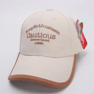 Detail of vintage beige canvas kids baseball cap with brown piping and embroidered letters