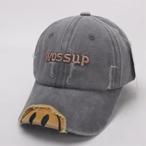 Detail of grey washed baseball cap featuring WOSSUp embroidery and yellow smiley patch