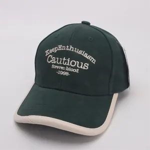 Detail of green kids baseball cap with white 3D letter embroidery and beige brim piping