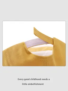 Detail des verstellbaren Klettverschlusses und Baumwollfutters der gelben Babykappe