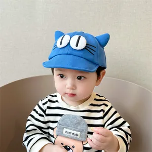 Close-up of blue baby baseball cap featuring cartoon cat ears and large eye embroidery