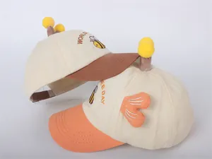 Detalle del bordado WORLD BEE DAY en gorras para niños con alas y antenas decorativas