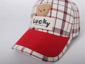 Detailed view of kids' red plaid baseball cap with plush bear patch and Lucky label