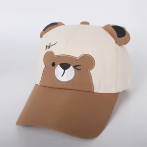 Detail of a beige kids baseball cap featuring cute bear ears and hi embroidery
