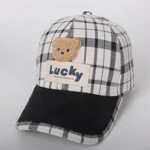 Detail of checkered kid's baseball cap featuring a plush bear patch and Lucky embroidery