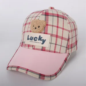 Detail of red and white checkered kids baseball cap with plush bear patch and Lucky label