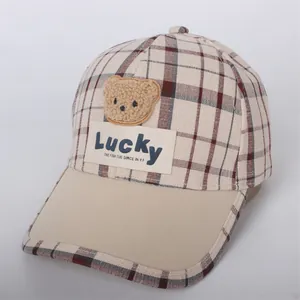 Detail of children's plaid baseball cap with plush bear patch and Lucky label