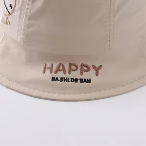 Close-up of cute dinosaur and happy letter embroidery on beige cotton sun hat