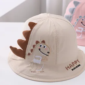 Detailed close-up of cartoon dinosaur embroidery on a beige cotton baby sun hat