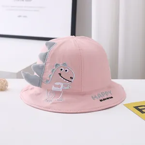 Close-up of pink cotton bucket hat with cartoon dinosaur patch and Happy embroidery