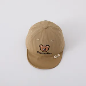 Detail of baby baseball cap with cute bear embroidery and soft khaki cotton fabric