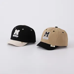 Detail of children's cotton baseball caps featuring 'M' embroidery and short brims