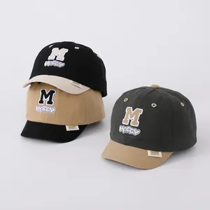 Close-up of embroidered M and HAPPY logo on cotton soft brim baby baseball caps
