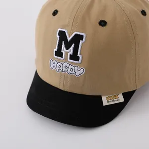 Detail of embroidered letters M and HAPPY on khaki and black kids' baseball cap