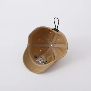 Detail view of khaki cotton baseball cap interior showing embroidery and adjustable cord