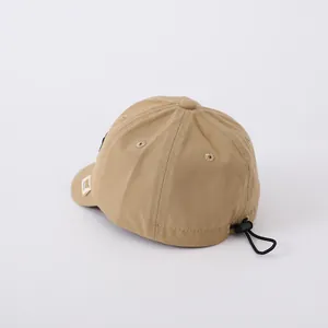 Detail of tan cotton baseball cap with adjustable rear elastic drawstring and toggle