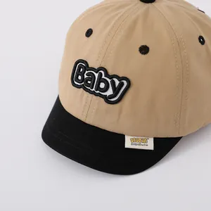 Detail of color-block baby baseball cap showing Baby embroidery and woven label texture