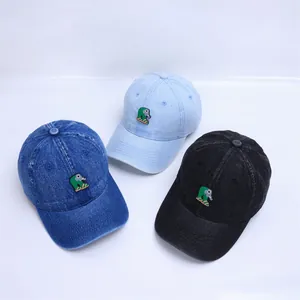 Detail of three denim baby baseball caps in blue and black with green elephant embroidery